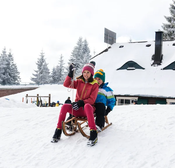 Día de invierno con nieve y niños felices descendiendo por la pendiente del trineo —  Fotos de Stock