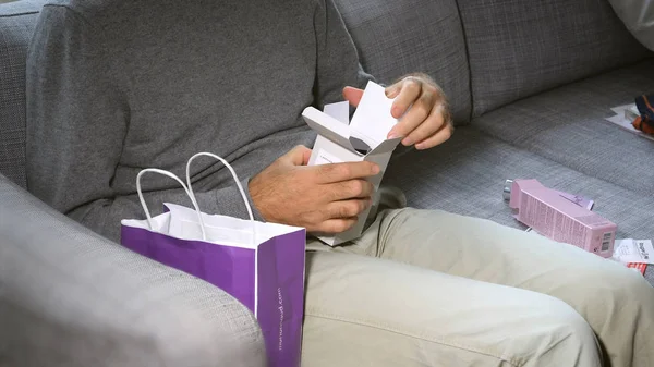 Man unboxing di sofa kosmetik yang berisi Parfum LArtisan — Stok Foto