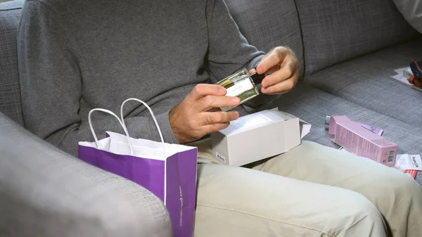 Hombre unboxing en el sofá cosméticos que contienen LArtisan Parfume — Foto de Stock