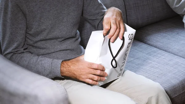 Homem unboxing no sofá cosméticos contendo mercadorias — Fotografia de Stock