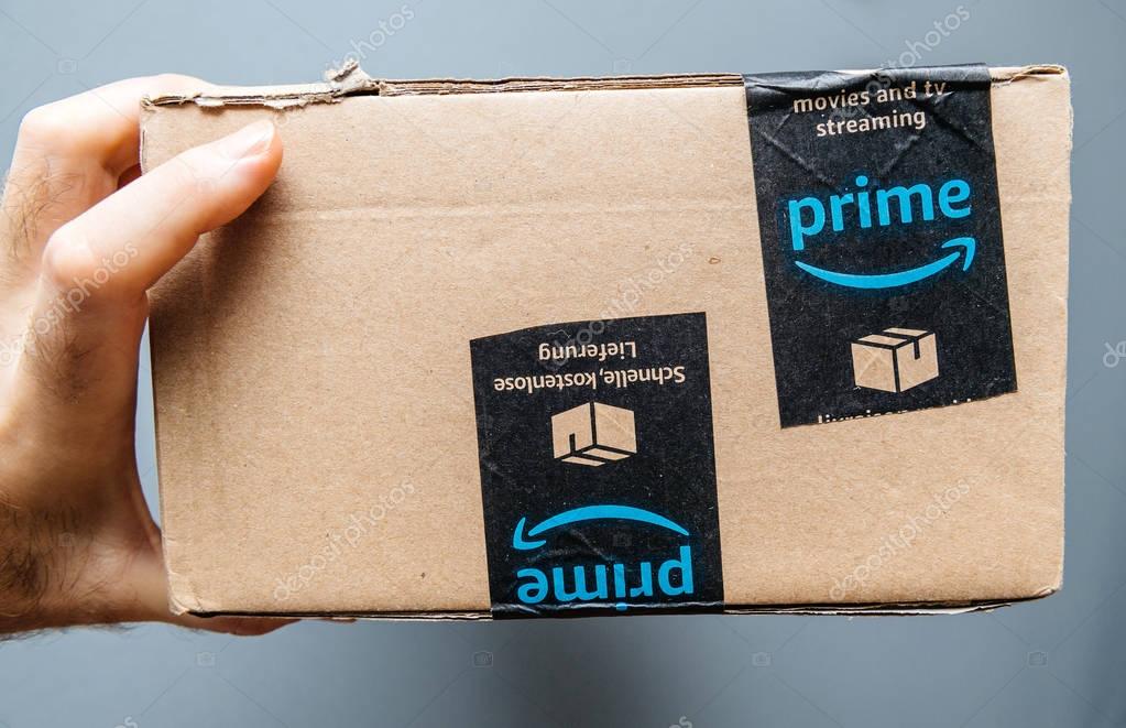 PARIS, FRANCE - JAN 6, 2018: Hand holding cardboard box with Amazon Prime scotch protection band