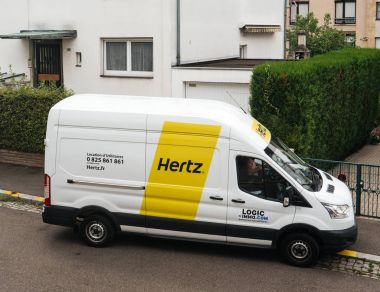 White HERTZ rent a van service seen from above on a French stree clipart