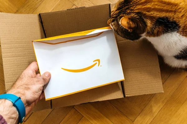 Человек распаковывает картон Amazon.com, содержащий неожиданный конверт — стоковое фото