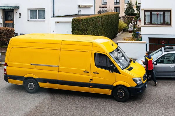 Φορτηγό παράδοσης DHL στο δρόμο με Κούριερ που εισέρχονται το κίτρινο van — Φωτογραφία Αρχείου