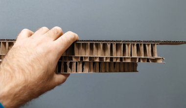 Holding ve gri arka planı birden fazla kalınlık yığınını inceliyor fabrika işçisi erkek el Oluklu karton karton kağıt ambalaj için 