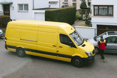 Paris, Fransa - 30 Mar 2018: Erkek kurye paket parsel tipik Avrupa Mahallesi - yükseltilmiş görünümü içinde teslim zamanında teslim sonra Dhl sarı teslim van girer 