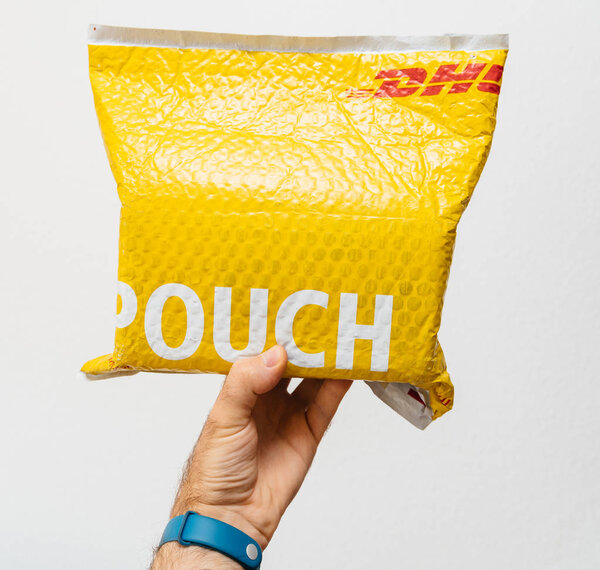 ПАРИЖ, Франция - 24 марта 2018 года: Мужская рука держит на белом фоне желтый пакет DHL Express
