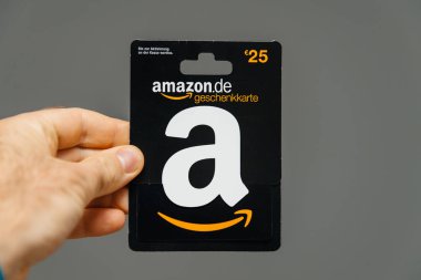 Paris, Fransa - 1 Nisan 2018: gri arka plan 25 Euro Amazon hediye kartı Amazon Almanya, Avusturya'da de geçerli tarafından verilen karşı tutan adam
