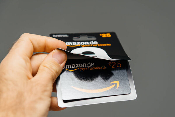 PARIS, FRANCE - APR 1, 2018: Man opening 25 Euros Amazon gift card issued by Amazon Germany, valid in Austria as well