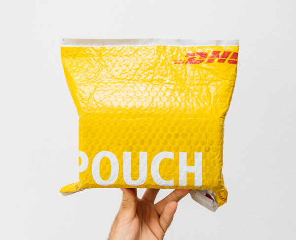 ПАРИЖ, Франция - 24 марта 2018 года: Мужская рука держит на белом фоне DHL Express желтый пакет пластиковый пакет
