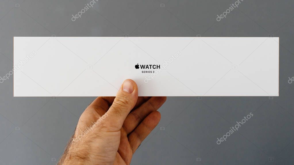 PARIS, FRANCE - APR 15, 2018: Point of view at front side Apple Watch wearable smartwatch cardboard box in man hand against gray background
