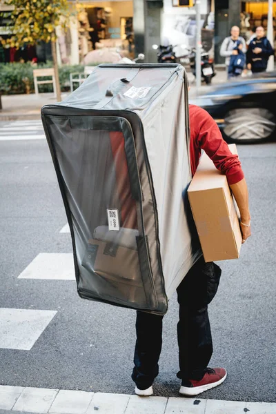 Young man carrying on his back an extra-large see-through delivery — Stock Photo, Image