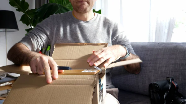 Curioso uomo unboxing disimballaggio Amazon sul divano del soggiorno — Foto Stock