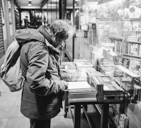 Side view of mid-adult man reading a book on the outdoor shelves — Stockfoto