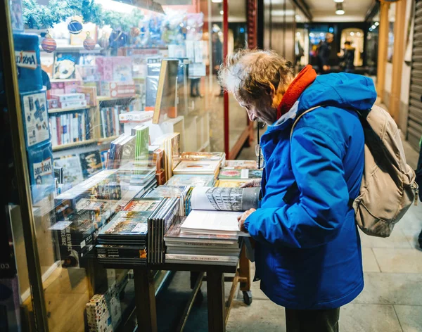 Mężczyzna w średnim wieku czyta książkę na zewnątrz półki — Zdjęcie stockowe