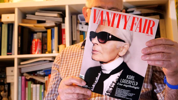 Homem sênior lendo cuidadosamente mais recente número francês Vanity Fair — Fotografia de Stock
