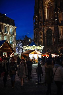 Pazar tezgahları ile dikey görüntü gece sahnesi Chalets Place de la Cathedrale 'de satılık çok sayıda oyuncak ve hediyelik eşya ve gezici atlı karınca insanlar