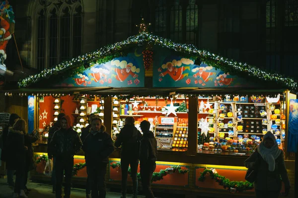 Noční scéna s řadou stánků chaty s více hračkami a suvenýry na prodej v Place de la Cathedrale Notre-Dame s turisty místní obyvatelé okružní — Stock fotografie