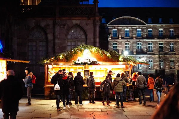 Marktkraam chalet met meerdere speeltjes te koop in Place de la Cathedrale Notre-Dame met toeristen die de iconische jaarlijkse markt bewonderen — Stockfoto