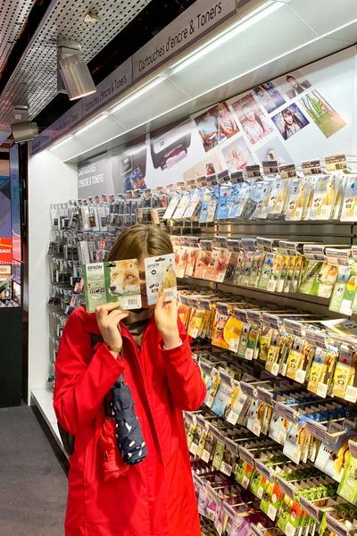 Donna in cappotto rosso nasconde il suo volto dietro l'inchiostro Epson per le stampanti a getto all'interno del centro commerciale FNAC negozio elettronico francese prima di offerte Venerdì nero — Foto Stock