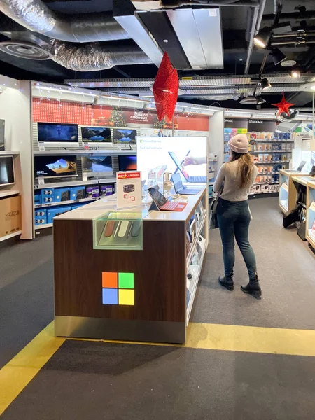 Visão traseira da mulher comprando Vários tablets Microsoft Surface e notebooks para venda em dedicado Microsoft stand dentro FNAC francês loja eletrônica shopping antes de Black Friday — Fotografia de Stock