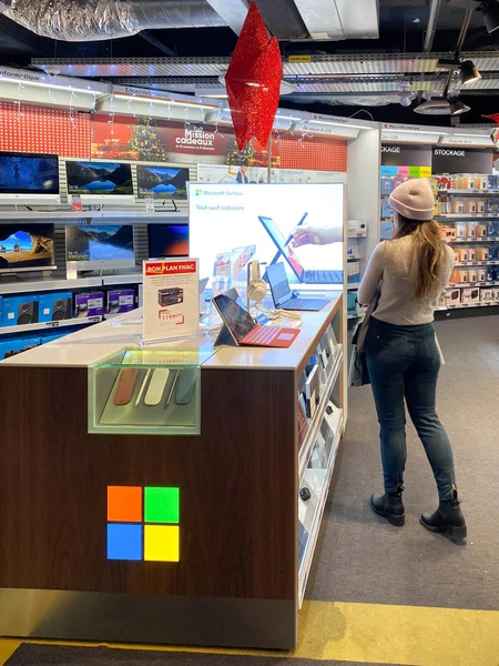 Kara Cuma 'dan önce Fnac Fransız elektronik mağazasının içindeki Microsoft standında satışa sunulan birden fazla Microsoft yüzeysel tablet ve defterlere hayran olan bir kadın. — Stok fotoğraf