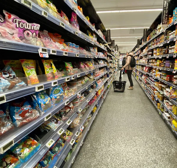 Carrito de compras mirando estantes con múltiples dulces alimentos — Foto de Stock