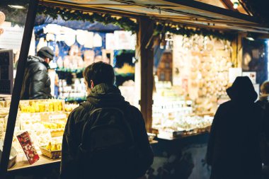 Yıllık Noel Pazarı sırasında Merketstall köşkünde satılık Noel oyuncaklarına bakan genç turist kadının arka manzarası