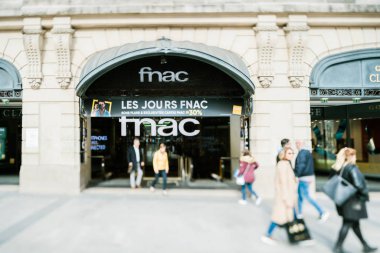 Paris 'in merkezinde Champs Elysee Bulvarı' nda Fnac Elektronik ve kitabevinin önünde yürüyen yayaların üzerinde tilt vites lensi kullanılıyor.