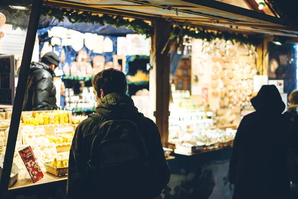 在一年一度的圣诞市场上，年轻的观光客妇女在市场的货摊上看圣诞玩具的背景图 — 图库照片