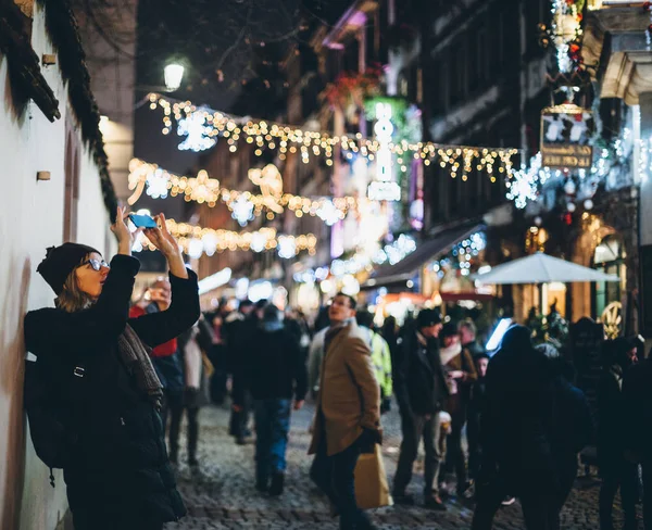 Noel Pazarı için Maroquin sokağının işlek sokağında fotoğraf çeken genç bir turist. Noel Pazarı için aydınlatıcı. — Stok fotoğraf