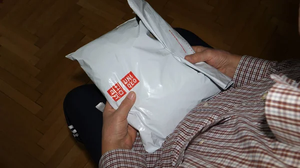 Старший чоловік розпаковує пластиковий пакет Uniqlo магазини — стокове фото