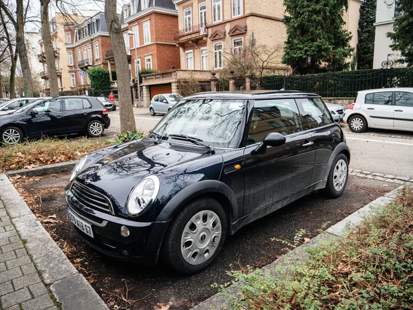 Black Mini Cooper car parked on city street with luxury mansions houses in background — Stock Photo, Image