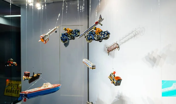 Street view of multiple toys hanged in the showcase of toy store - motorcyclists, boats, rockets, trains — Stock Photo, Image