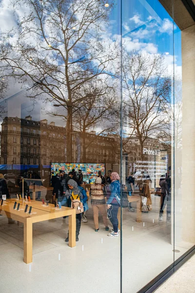 View from the street of people inside admiring latest smartphones and computers glass showcase of the iconic Apple Store on Champs Elysee — Stock Photo, Image