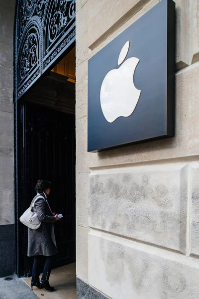 Vrouw komt de winkel binnen met Apple Computers logotype insignes naast de ingang van de iconische Apple Store op Champs Elysee - kantelbare lens gebruikt — Stockfoto
