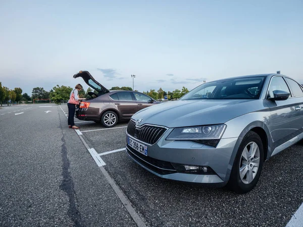 Large IKEA furniture parking with two Skoda cars Octavia and Superb parked in the evening - woman loading goods in trunk — ストック写真