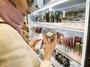 Parfüm mağazasından birden fazla makyaj malzemesi alan kadınların yan görünümü Alverde ürünlerini test ediyor.