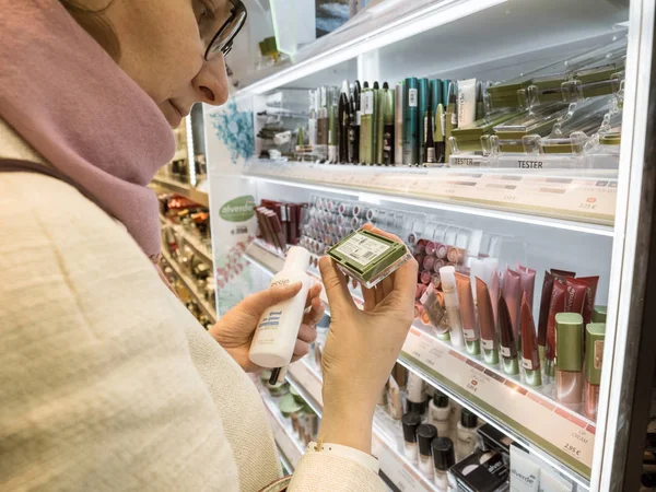 Seitenansicht einer Frau, die mehrere Make-up-Accessoires in einem Parfümeriegeschäft kauft, um Alverde-Produkte zu testen, die mehrere Produkte testen — Stockfoto