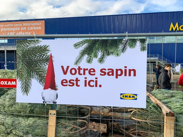 Mehrere Tannenbäume zum Verkauf durch Stahl und Holzzaun vor dem Möbelhaus Ikea geschützt und Text übersetzt als Ihr Weihnachtsbaum ist hier — Stockfoto