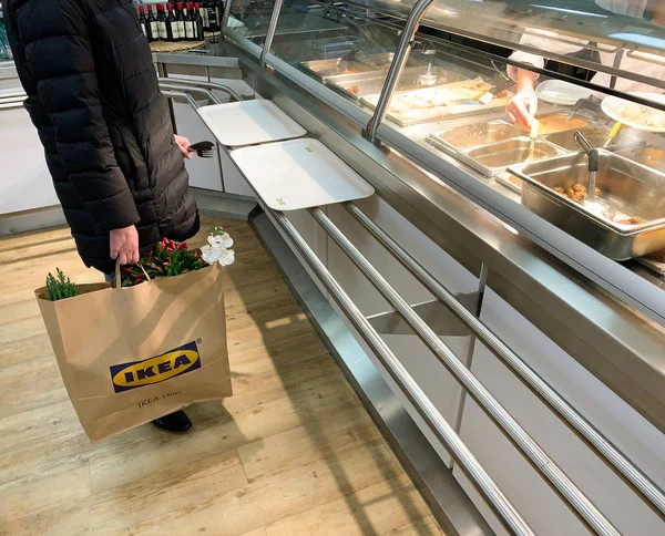 Tampilan samping dari wanita yang tidak dikenal menunggu di antrian di meja restoran IKEA menunggu untuk menempatkan pesanan bakso swedia — Stok Foto