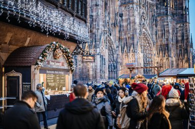 Strasbourg şehir merkezindeki Noel Pazarı 'nı keşfeden büyük bir grup insan. Arka planda Notre-Dame katedrali ve Maison Kammerzell' den yemek gurme dağ evi.