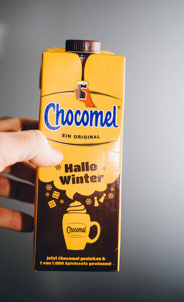 man hand holding yellow pack of Chocomel chocolate drink against gray background Hallo Winter edition - Dutch dirnk