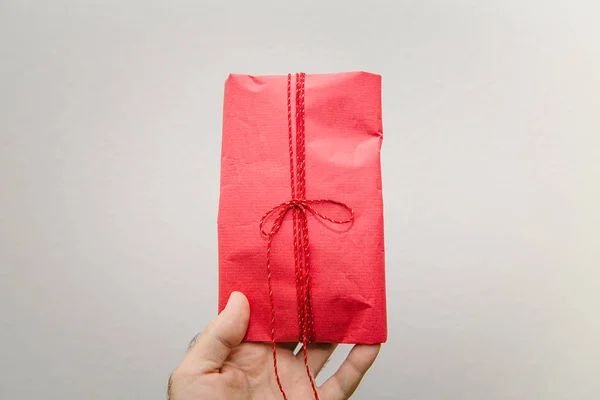 POV Man hand holding against white background beautifully packaged red gift present for the upcoming birthday valentine new year christmas Hanukkah black friday holiday — Stock Photo, Image