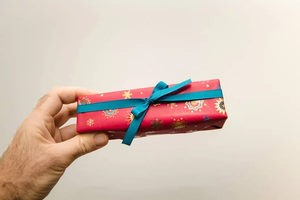POV Man hand holding against white background beautifully packaged red gift present for the upcoming birthday valentine new year christmas Hanukkah black friday holiday — ストック写真