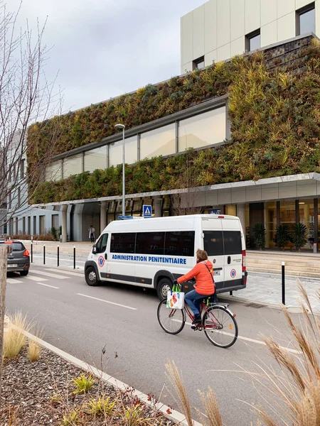 Wanita pengendara sepeda di dekat van putih Fiat Ducato dengan Administration penitentiaire en France menerjemahkan administrasi penjara yang diparkir di depan rumah sakit NHC — Stok Foto