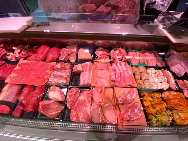 Vista interior del gran supermercado de alimentos Edeka con múltiples tipos de productos de carne fresca roja en los estantes — Foto de Stock