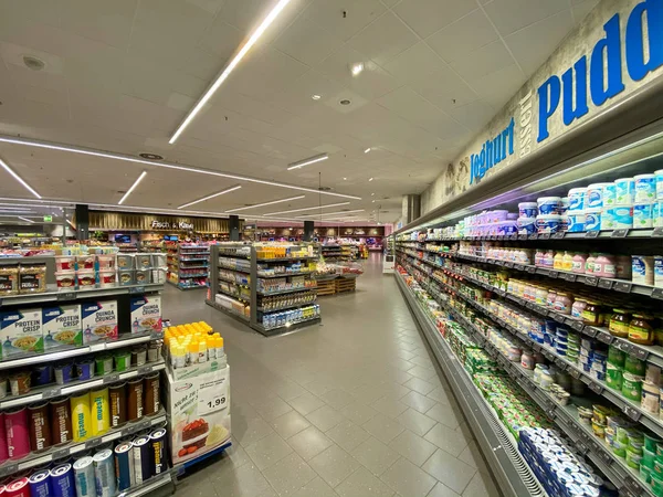 Leche fresca y artículos crujientes de proteínas - Vista interior del gran supermercado de alimentos Edeka con múltiples productos frescos en los estantes —  Fotos de Stock