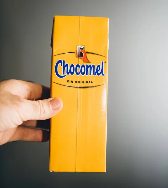 Man hand met geel pak chocolade Chocomel drank tegen grijze achtergrond — Stockfoto