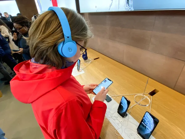 Apple Computer内の赤いコートのサイドビュー女性Dr.Dre Soloプロの新しいビートで音楽を聴くテストを保存アクティブノイズキャンセリングヘッドフォン — ストック写真